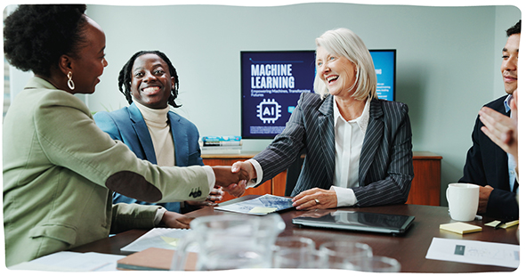 Four people at a boardroom table, two of them shaking hands, following a presentation on 'machine learning'