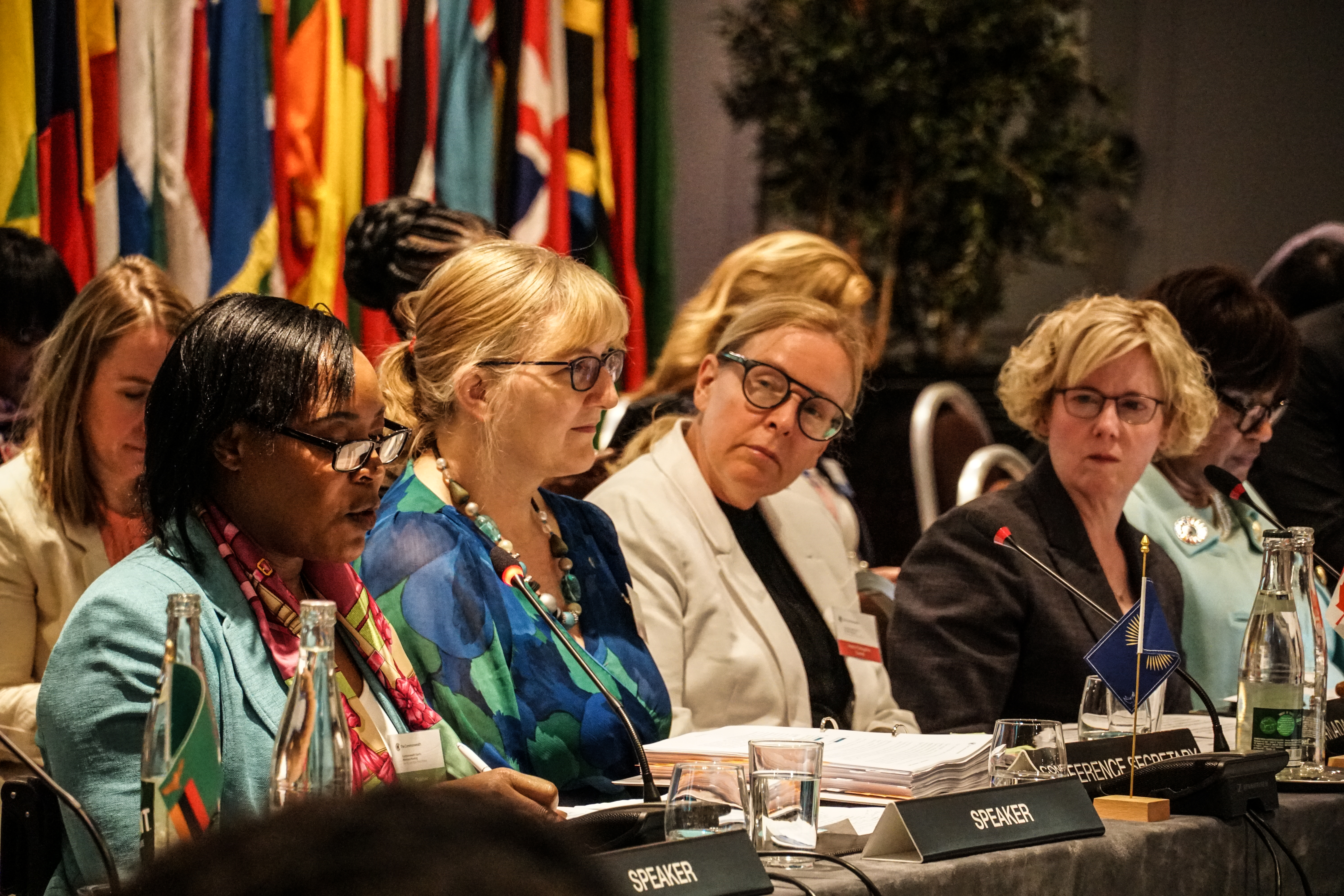 Carla Qualtrough sits on a panel of speakers, including Paralympian Anne Wafula Strike, at the 11th Commonwealth Sports Ministers Meeting in Paris. Commonwealth flags are visible behind them.
