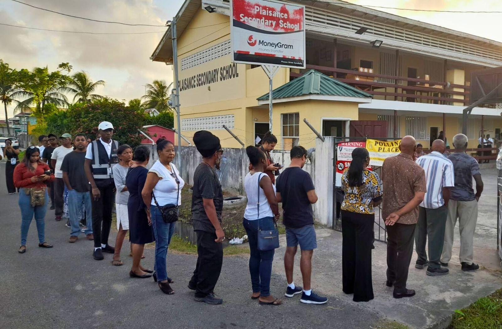 People stand in a queue to vote in the 2025 Guyana General and Regional Elections