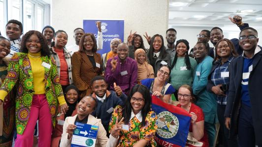 A large group of young people pose for a photograph; one person is holding the Belize flag