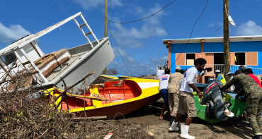 People move boat out of a road on the island of Carriacou after Hurricane Beryl