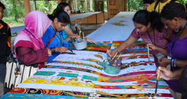 A group of young people paint colourful patterns onto fabric